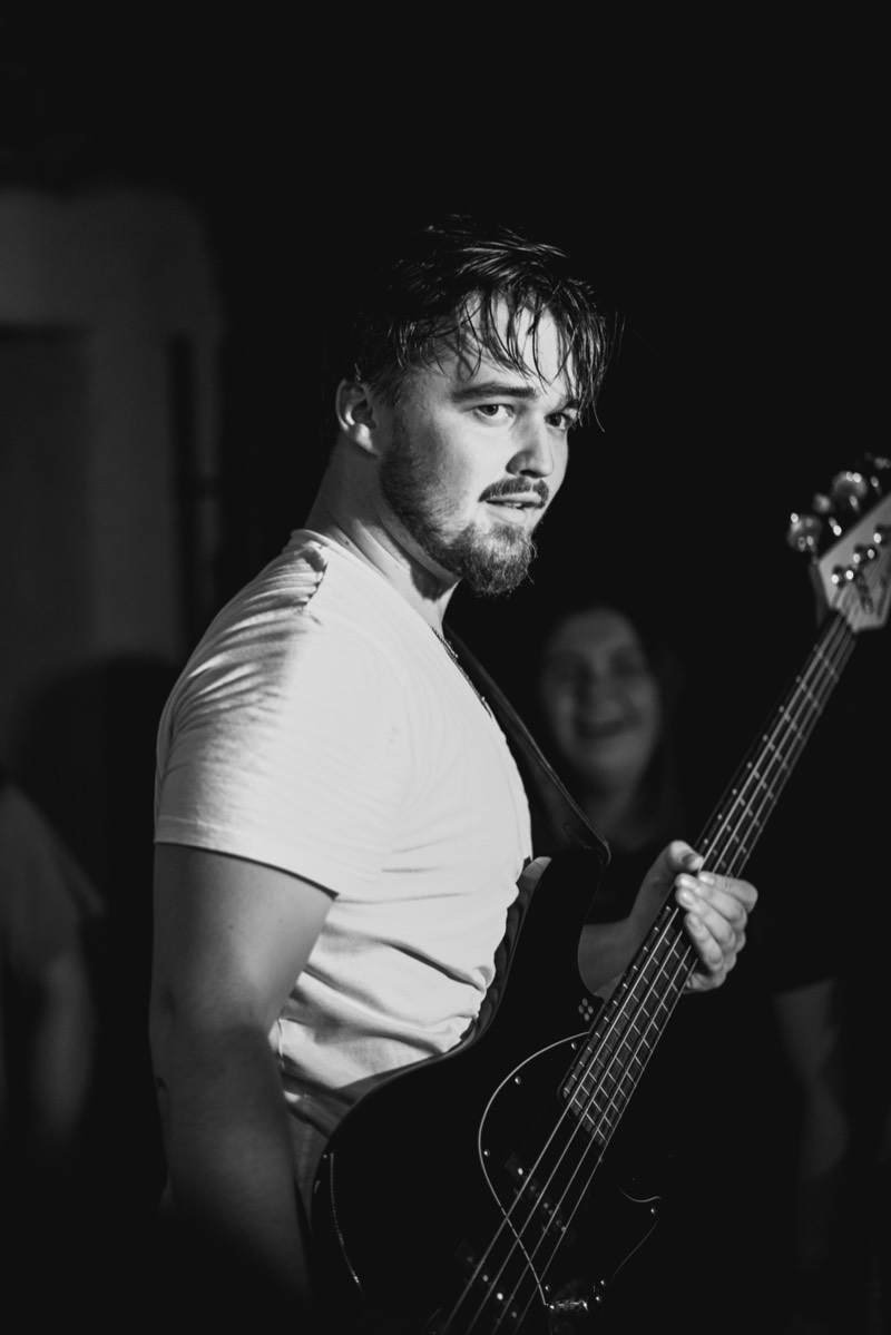 Josef Žemlička s baskytarou se dívá do objektivu, černobílá fotografie